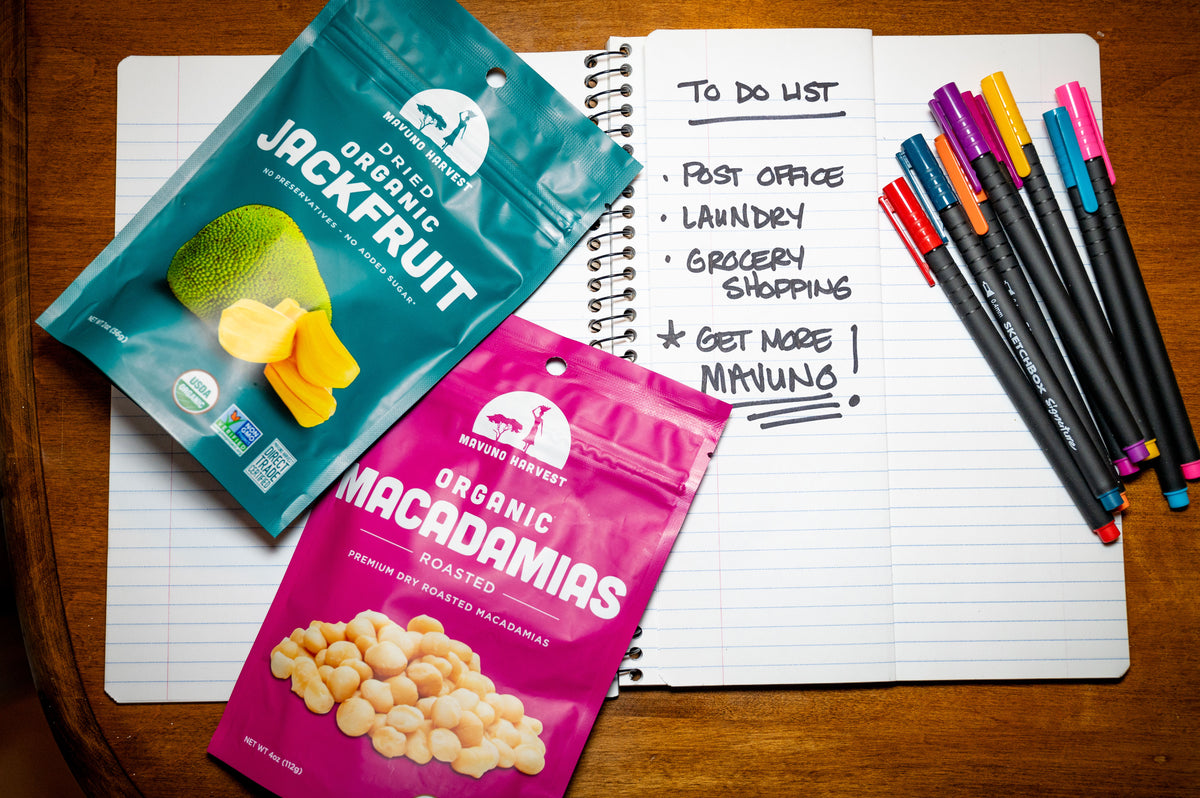 Mavuno Harvest jackfruit and macadamia snacks beside a notebook on a wooden table